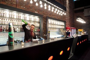 A bar area with shelves of bottled beverages, a bartender, and a counter with various bar tools and glasses. - Estrel Hotel Berlin (Berlin)