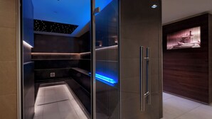 A modern bathroom with a glass enclosure, a built-in shelf, and a recessed ceiling light. - Estrel Hotel Berlin (Berlin)