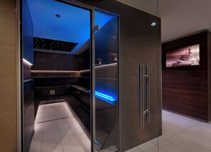 A modern bathroom with a glass enclosure, a built-in shelf, and a recessed ceiling light. - Estrel Hotel Berlin (Berlin)