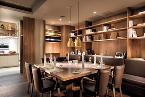 A modern dining area with a wooden table set for six, surrounded by leather chairs.