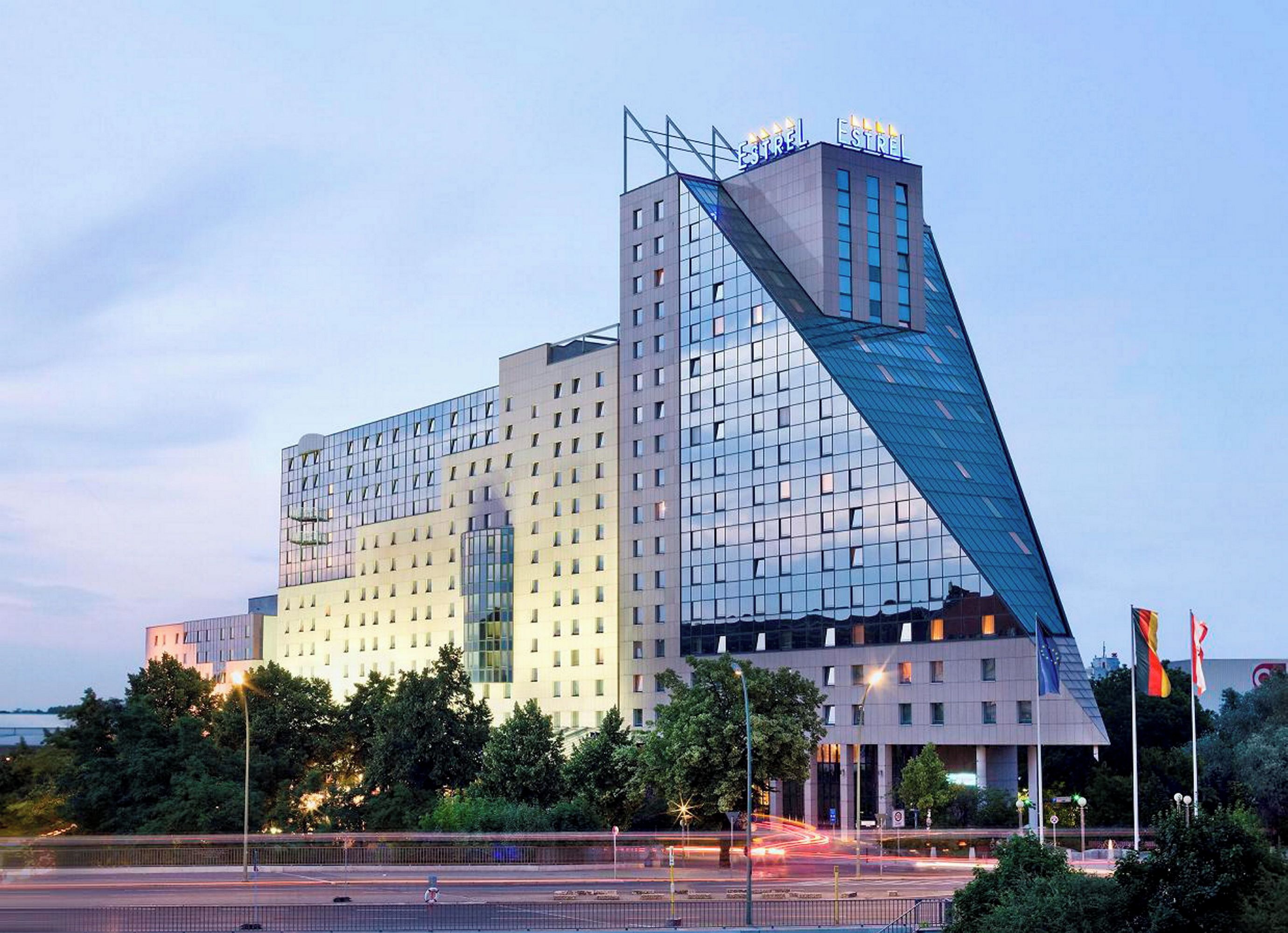 A modern hotel with a distinctive angular design, featuring a prominent glass facade and a rooftop structure.