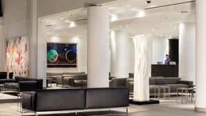 A modern lobby with a reception desk, seating area, and a large abstract painting. - Estrel Hotel Berlin (Berlin)