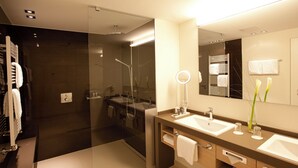 Ein modernes Badezimmer mit Duschkabine aus Glas, zwei Waschbecken und einem großen Spiegel.