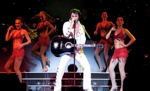 A stage with a performer and dancers, a guitar, and a microphone. - Estrel Hotel Berlin (Berlin)