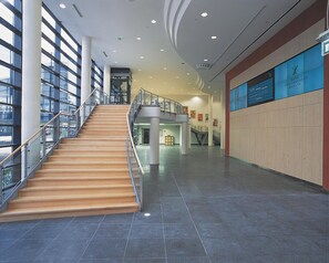 A spacious indoor area with a central staircase, large windows, and a modern design. - Estrel Hotel Berlin (Berlin)