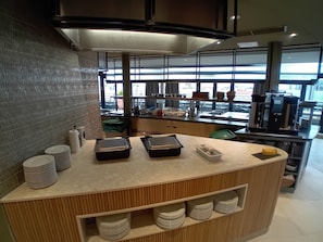 A modern kitchen with a central island, stainless steel appliances, and a view of the street. - Radisson Hotel Berlin Charlottenburg (Berlin)
