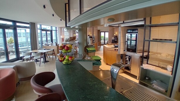 Un moderno vestíbulo de hotel con zona de bar, asientos y vistas al exterior.