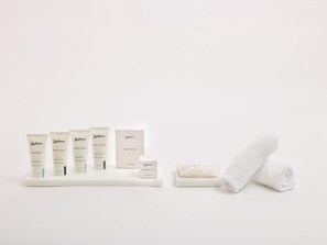 Un juego de artículos de aseo Radisson que incluye champú, gel de baño, acondicionador, loción corporal y un gorro de ducha, junto con una toalla enrollada.