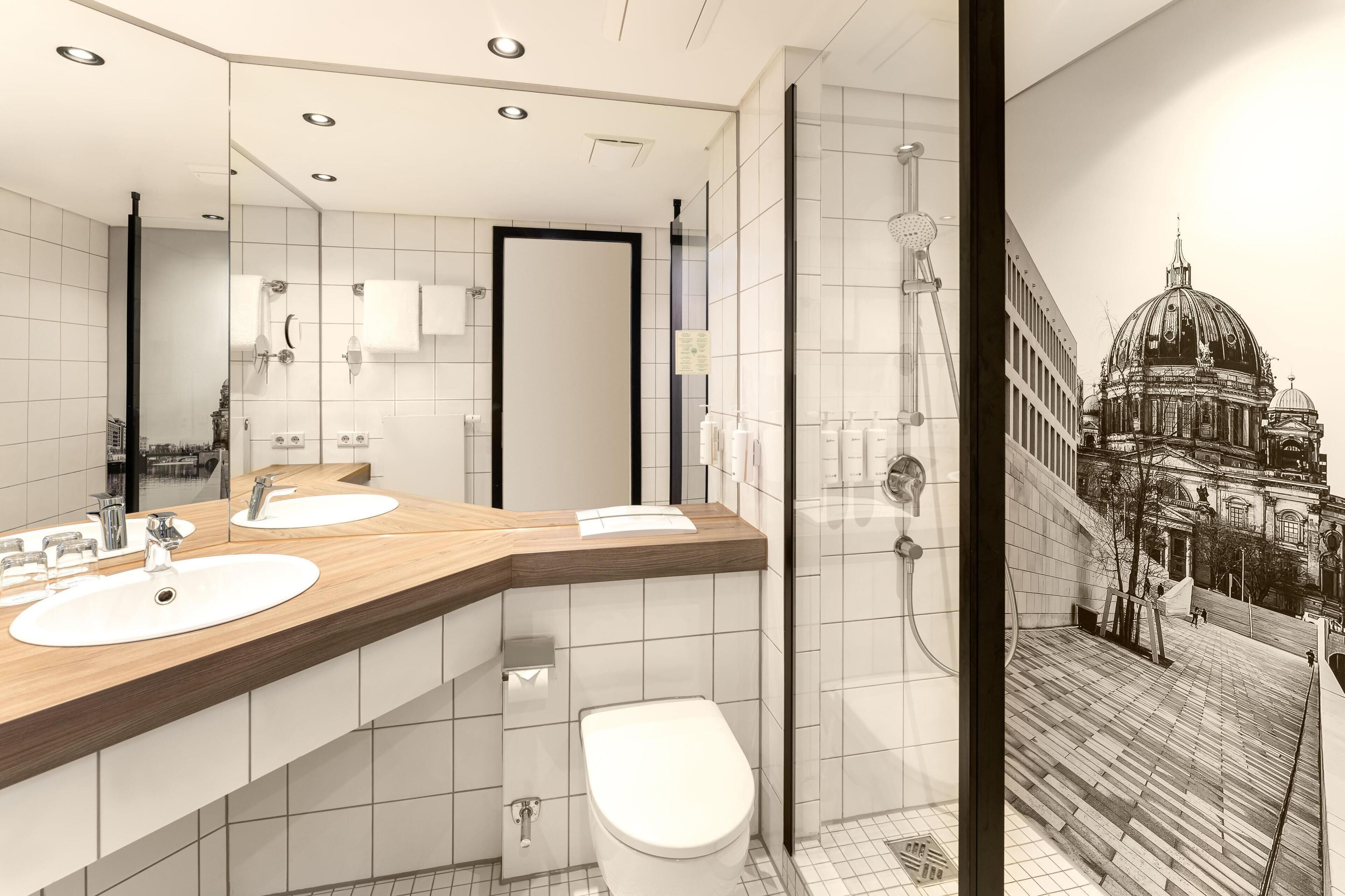 Een moderne badkamer met twee wasbakken, toilet en douche.