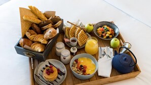 Bandeja de desayuno con bollería, gofres, fruta y tetera.