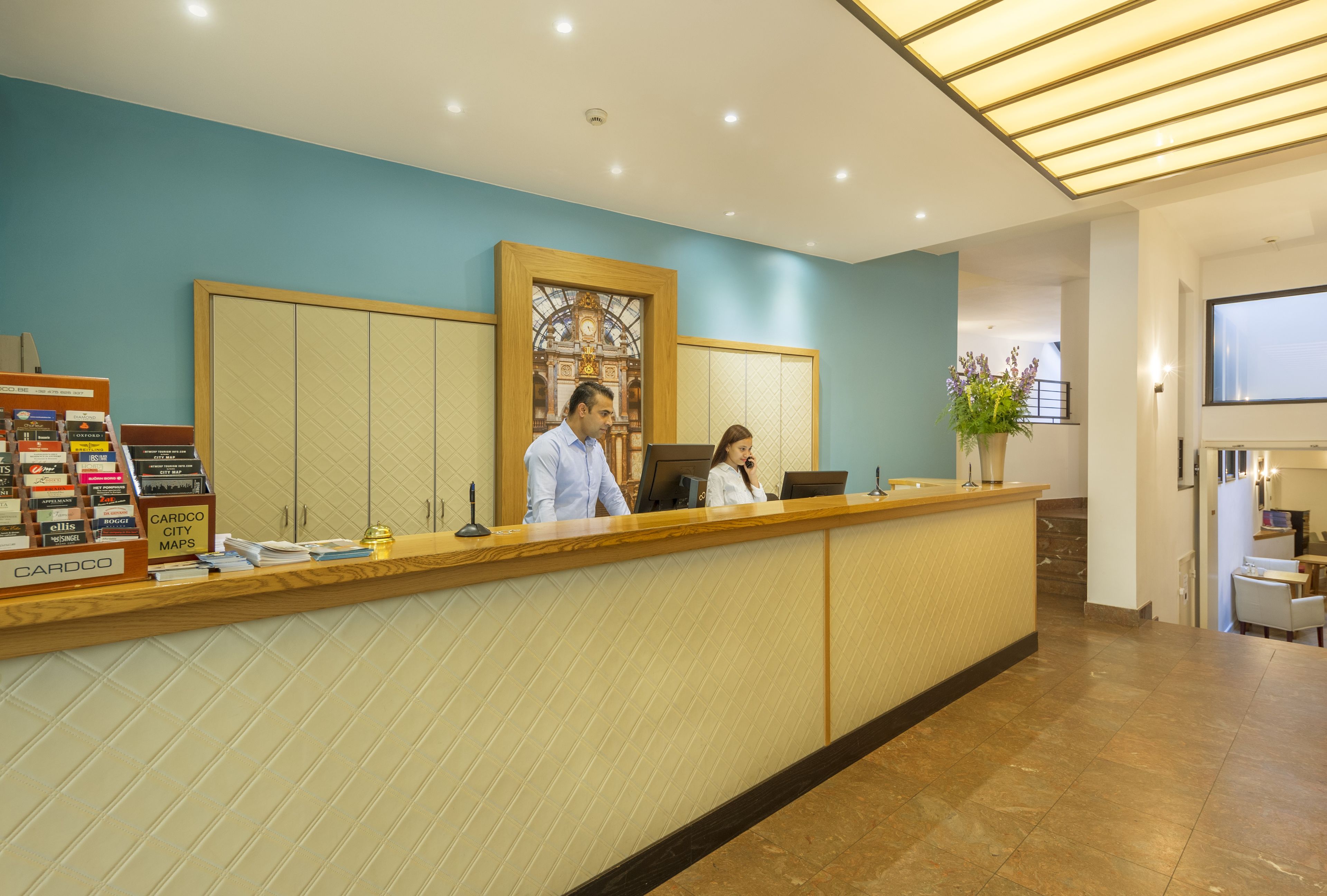 A reception desk with a wooden counter, a large stained glass window, and a sign for city maps.