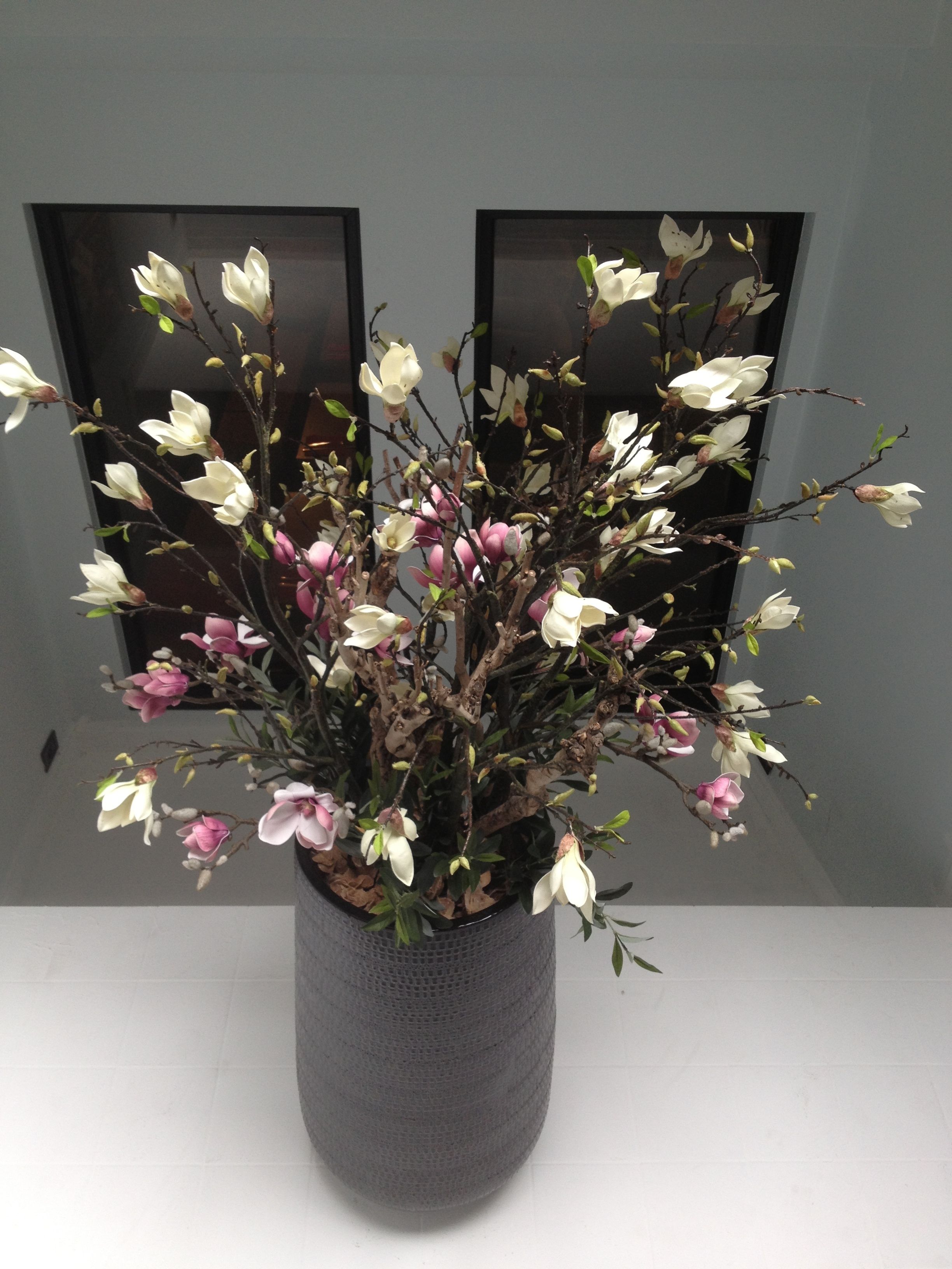 A potted plant with white and pink flowers in a textured grey pot.