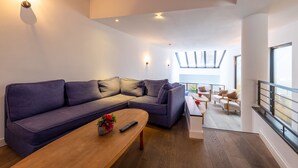 Una sala de estar moderna con un sofá seccional grande, una mesa de centro de madera y un comedor con una mesa y sillas blancas.