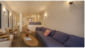 Una sala de estar moderna con un sofá, sillones, una mesa de centro y una escalera que conduce a un nivel superior.