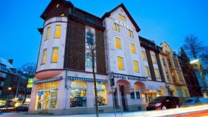 Um hotel de vários andares com design arquitetônico clássico, exibindo uma placa grande com a palavra 'HOTEL' na fachada.