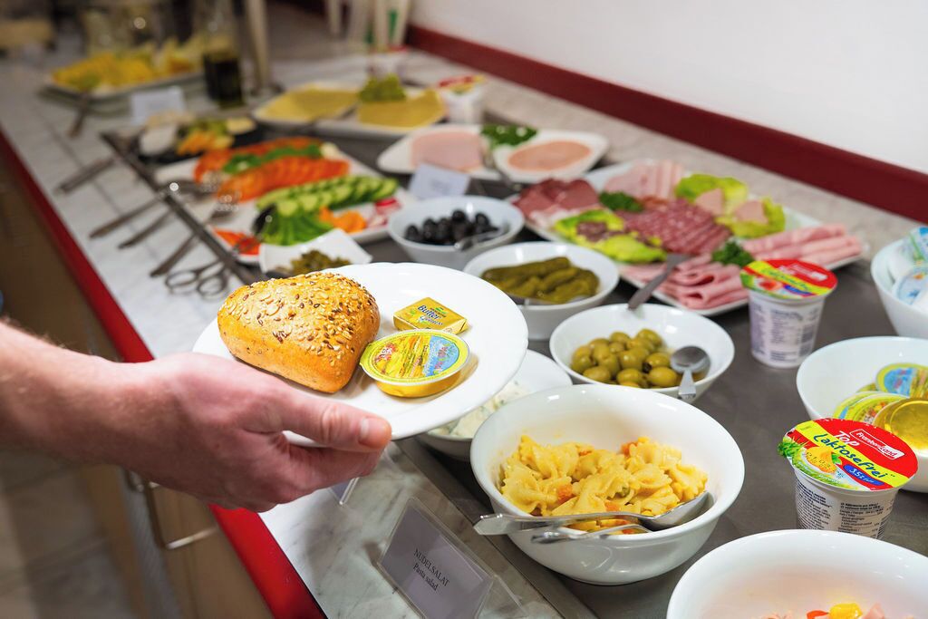 Un bufé con diferentes opciones de comida, entre ellas pan, queso, aceitunas y pasta.