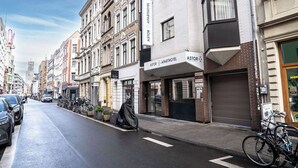 Une vue de rue avec une rangée de bâtiments, dont un hôtel-appartements Astor dont le portail du garage est fermé.