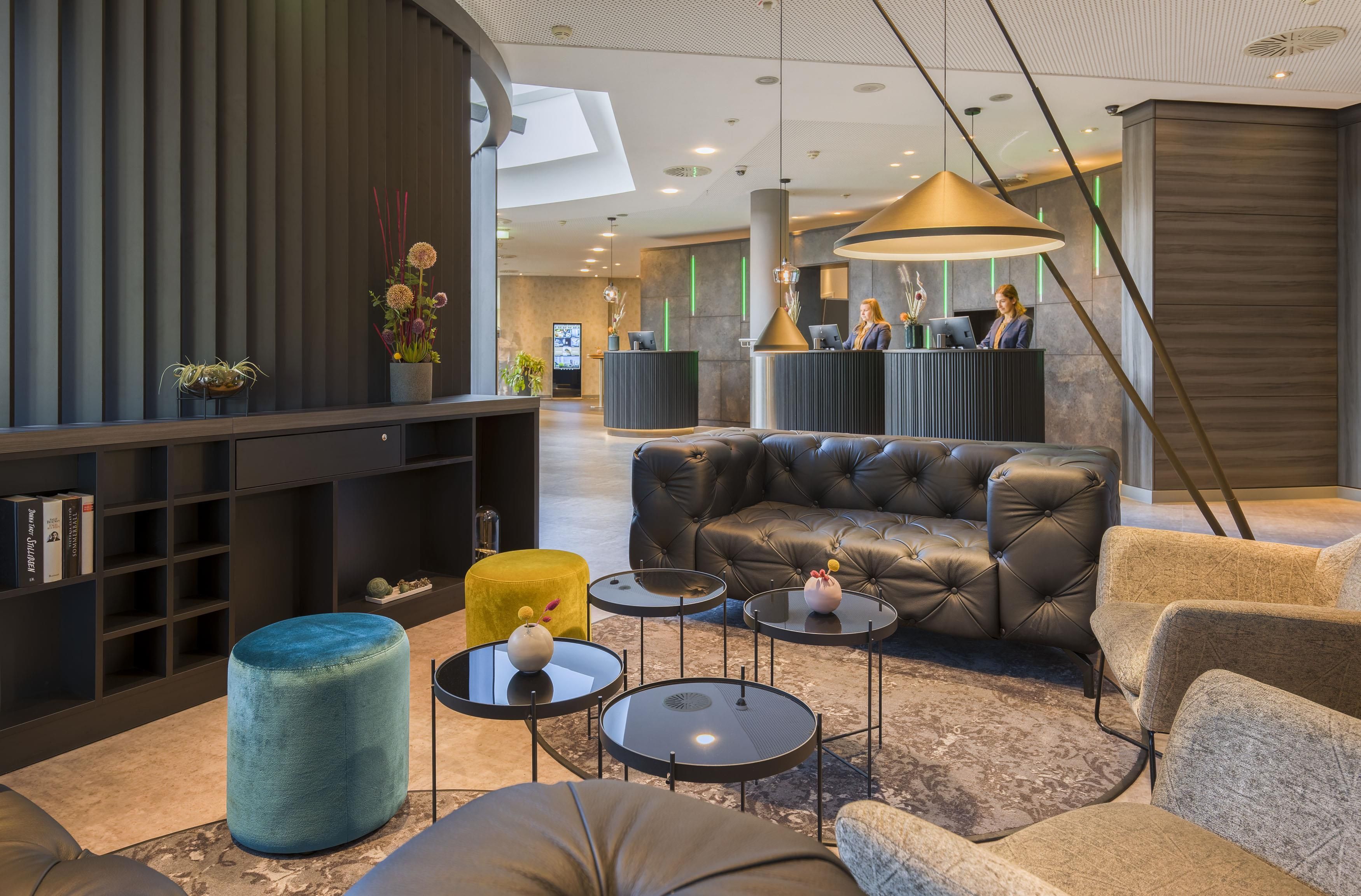 A modern lobby with a reception desk, seating area, and a bookshelf.