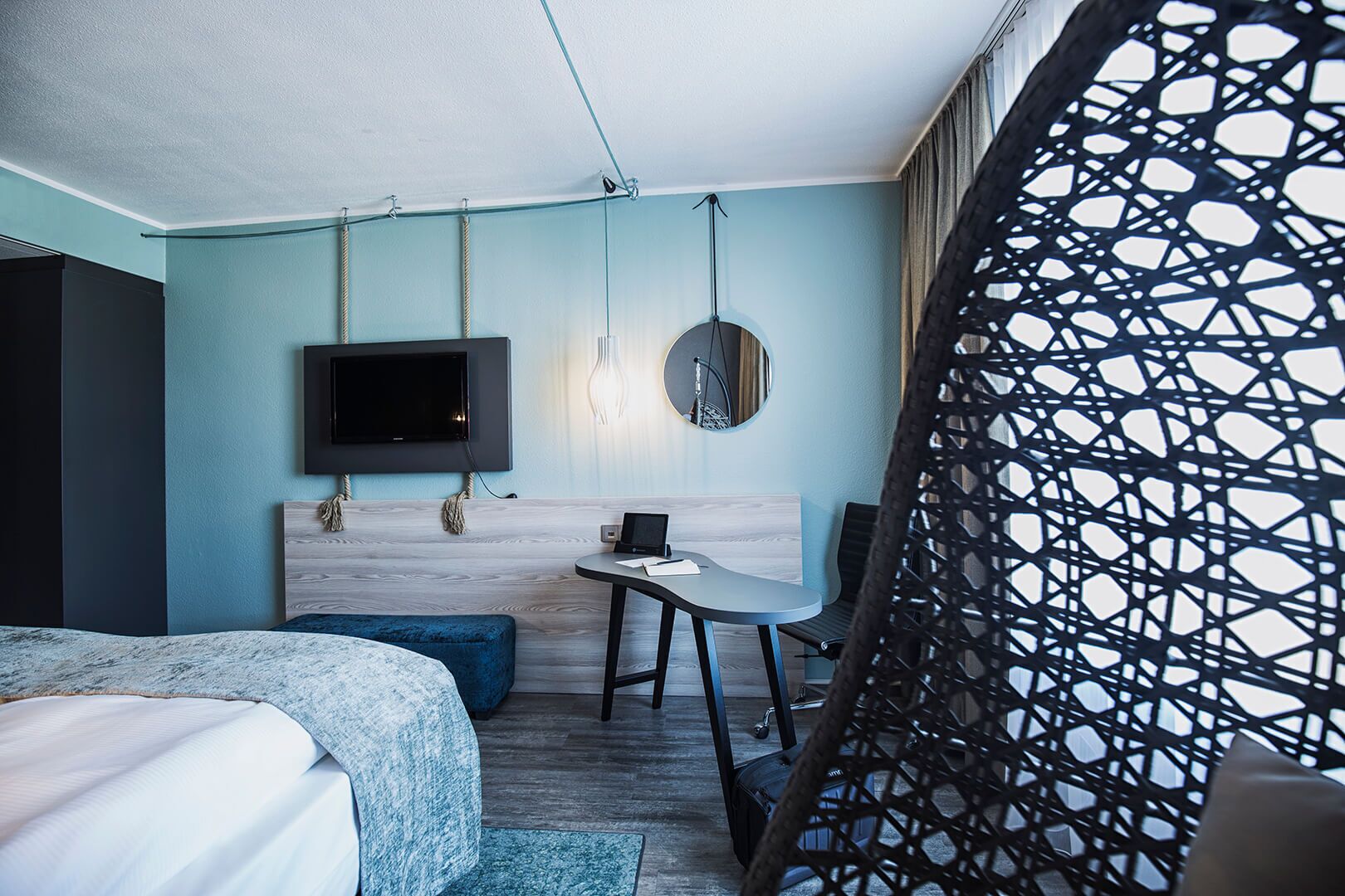 Una habitación de hotel moderna con cama, escritorio, televisor y un separador con diseño.