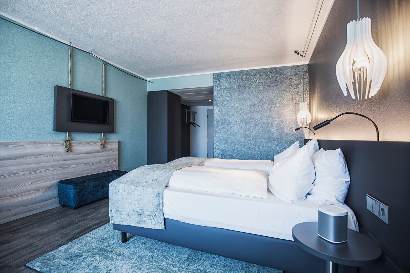 A modern bedroom with a bed, bedside table, and a mounted TV.