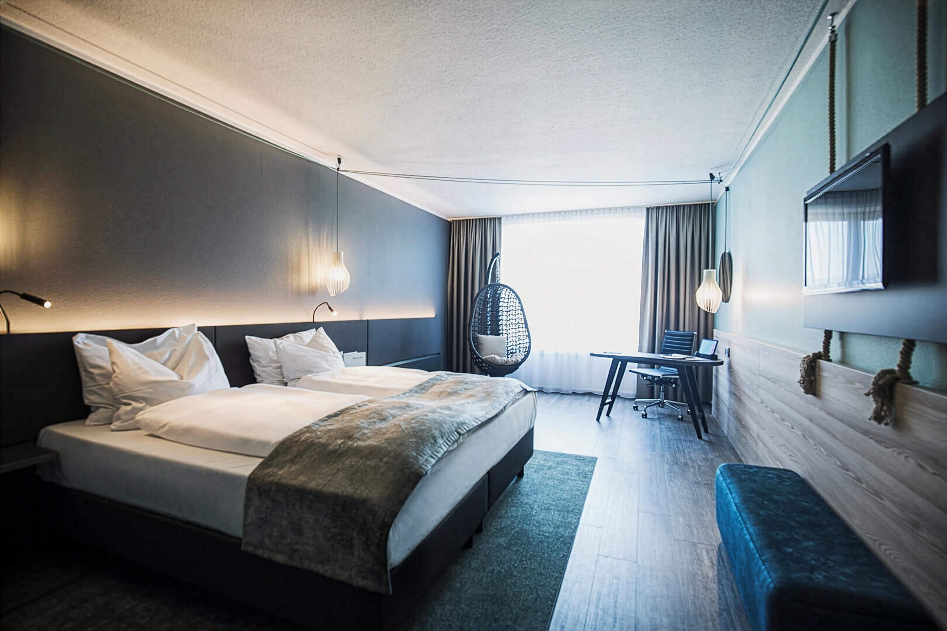 A hotel room with a bed, a desk, a chair, and a television.