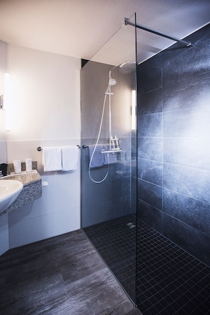 Een moderne badkamer met een douche met glazen wand, een wastafel en een handdoekrek.