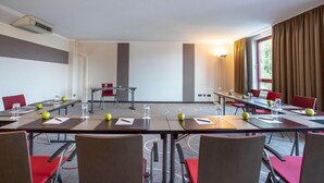 Een vergaderzaal met tafels, stoelen en een projectiescherm.