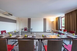 A conference room with tables, chairs, and a projector screen.