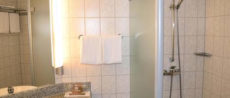 Ein Badezimmer mit Waschbecken, Spiegel, Handtuchhalter und Dusche.