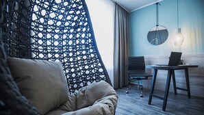 Een moderne kamer met een hangstoel, een bureau met een laptop en een ronde spiegel aan de muur.