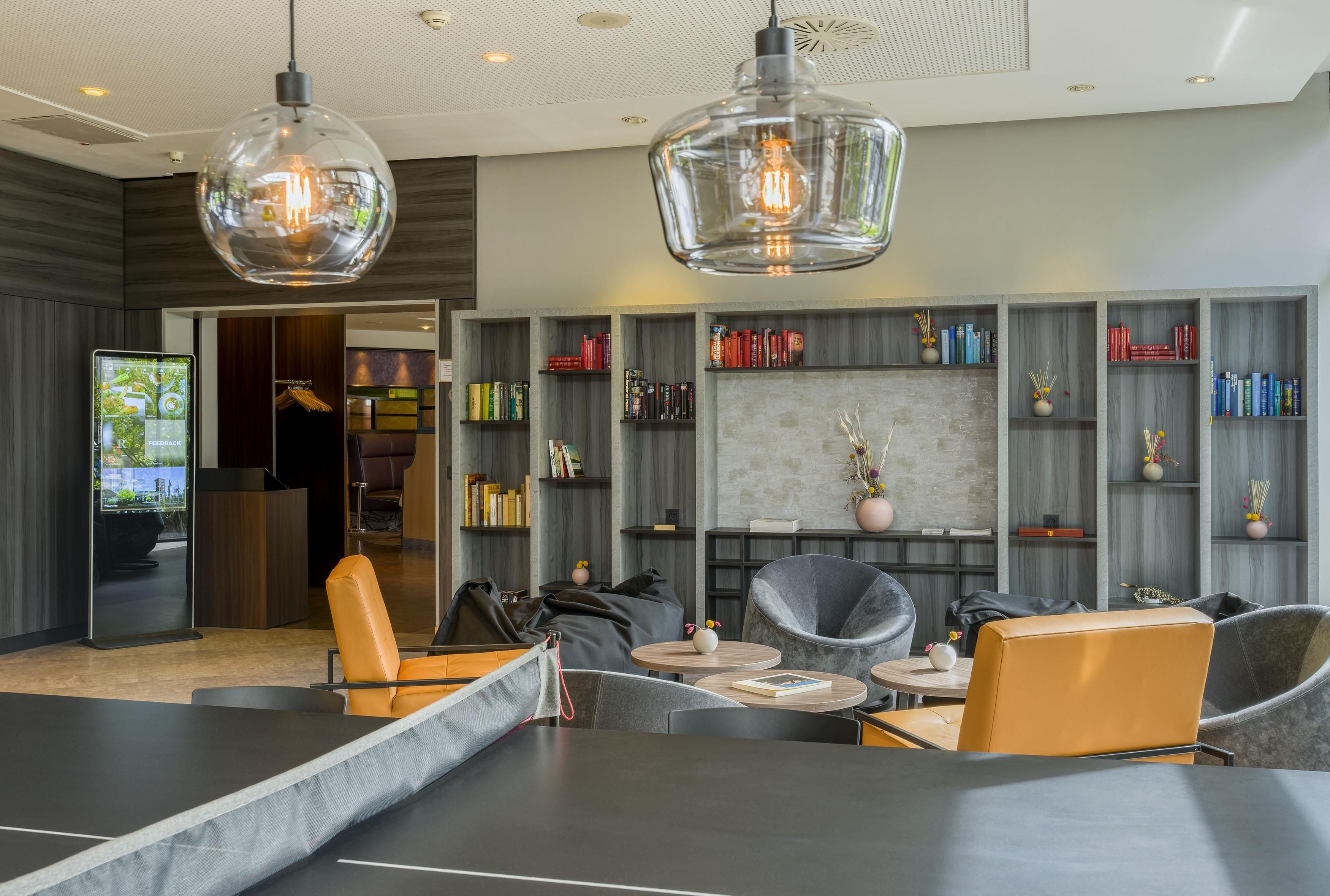 A modern lounge area with leather seating, a coffee table, and a bookshelf filled with books.