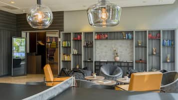 A modern lounge area with leather seating, a coffee table, and a bookshelf filled with books.
