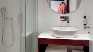Une salle de bain moderne avec une douche à parois de verre, un lavabo blanc et un miroir au-dessus.