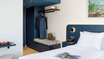 Une chambre d’hôtel avec un lit, une table de chevet, un fauteuil suspendu et une étagère fixée au mur.