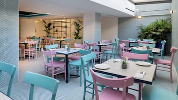 A modern dining area with colorful chairs and tables, a patterned floor, and a ceiling with skylights.