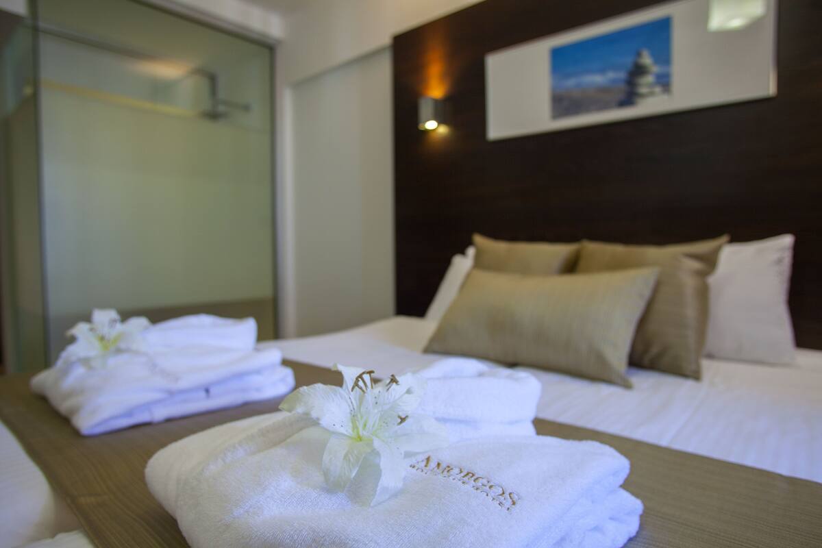 A hotel room with a neatly made bed, a wooden headboard, and a framed picture on the wall.