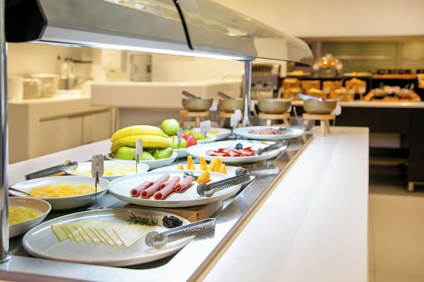 A buffet with various food items including fruits, cheeses, and meats.