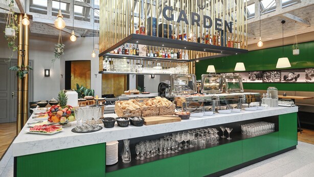 Un'area buffet con diverse pietanze e un angolo bar con bottiglie e bicchieri.