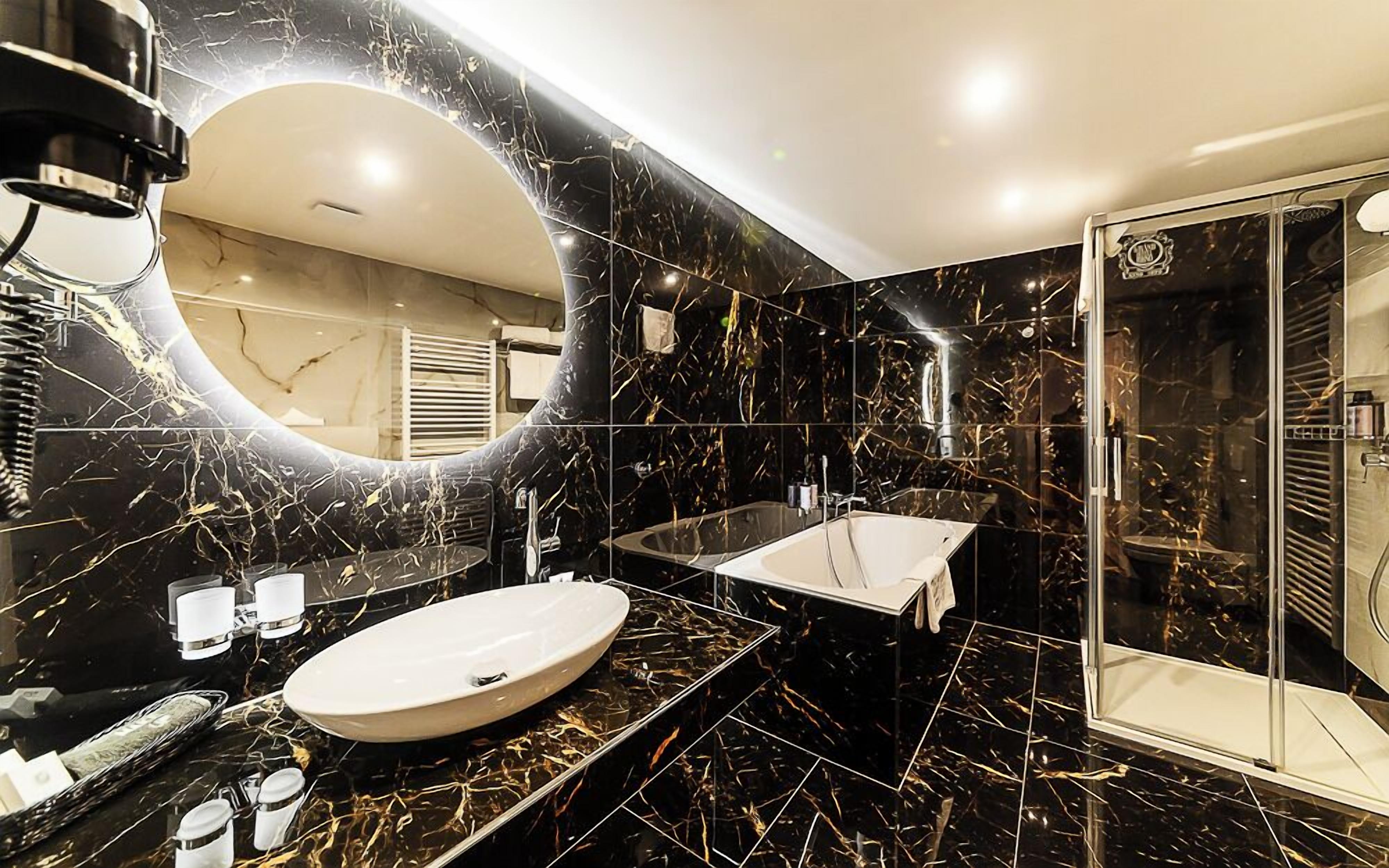 A modern bathroom with a large oval sink, a glass-enclosed shower, and a curved mirror.