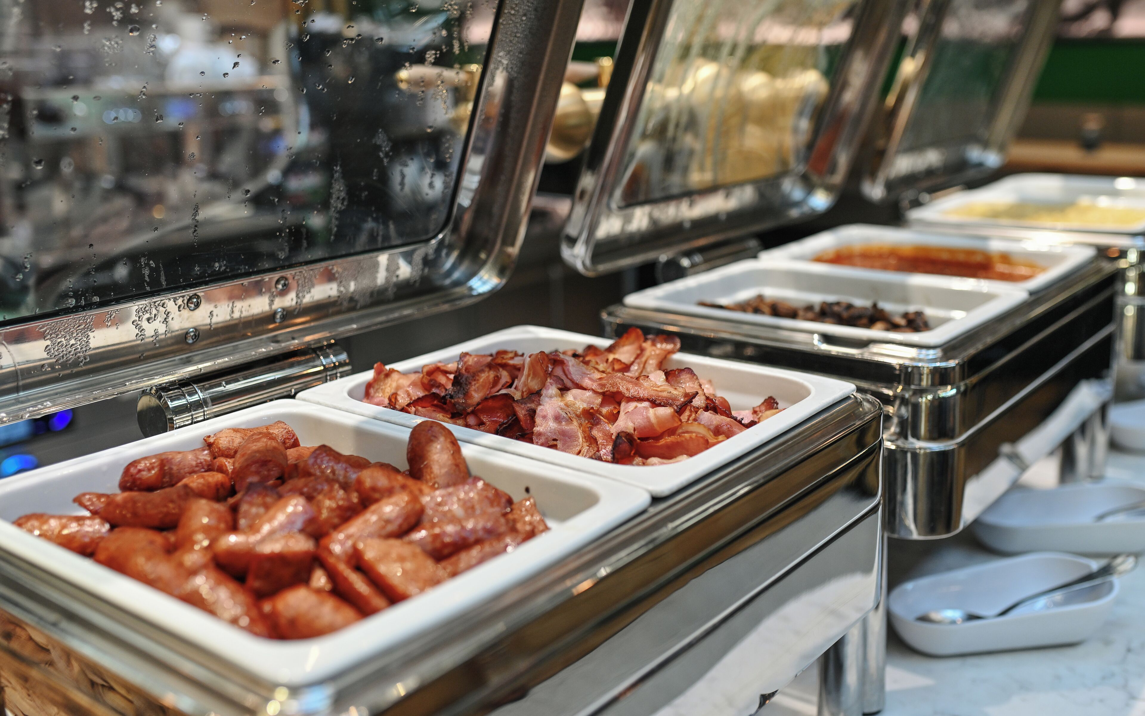 Un buffet proposant une variété de plats, notamment des saucisses et du bacon.