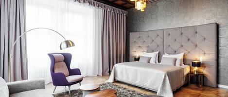 A modern bedroom with a tufted headboard, a large bed, a sofa, and a chair.