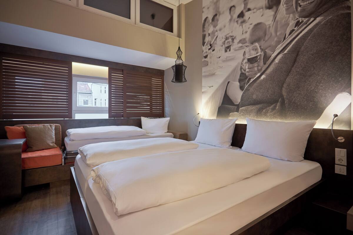 Habitación de hotel con dos camas, un sofá y un mural grande en la pared.