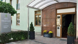 Exterior del Hotel Perlach Allee con un cartel de recepción, un área de estacionamiento y una entrada cubierta.