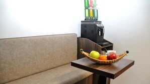 Un sofá y una pequeña mesa de madera con una cesta de frutas que contiene una manzana, una naranja y un calabaza.