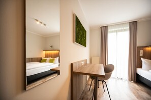 Una habitación de hotel moderna con cama, escritorio, silla y un espejo grande.