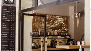 Un interior de cafetería moderna con un panel de menú, una barra y asientos.