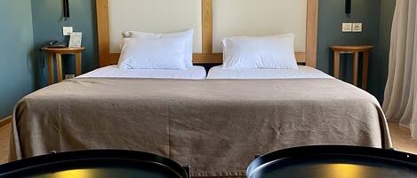 Habitación de hotel con una cama doble, dos mesitas de noche, dos lámparas y dos pequeñas mesas redondas.
