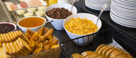 A buffet with various food items, including pastries, fruits, and beverages.