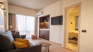 Una sala de estar moderna con un sofá, una mesita redonda y un televisor montado en la pared.