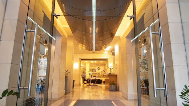 Un vestíbulo de hotel con una recepción, un área de espera y una entrada de vidrio.